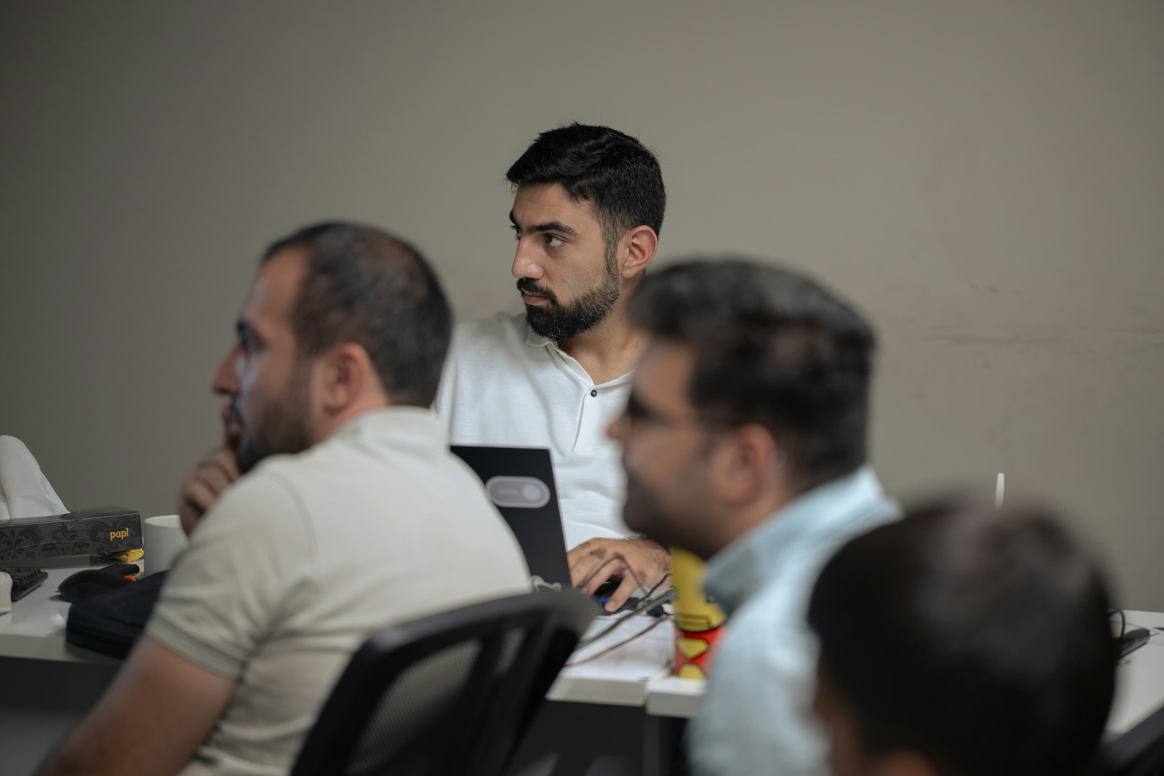 A cohort of legal professionals in a focused training session around a laptop